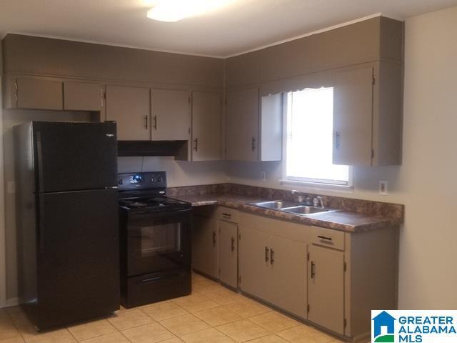 kitchen featuring black appliances, dark countertops, under cabinet range hood, and a sink