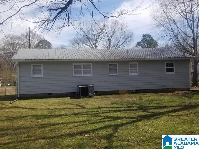 back of house with metal roof, a lawn, and central AC