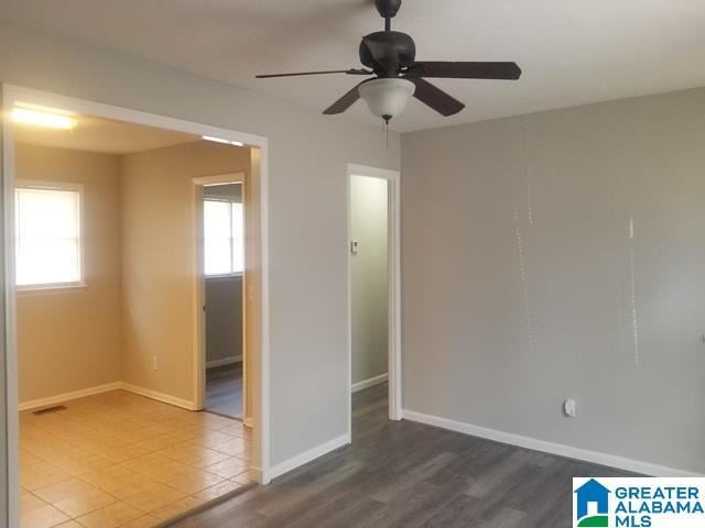 empty room featuring visible vents, ceiling fan, baseboards, and wood finished floors