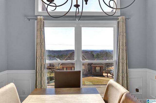 dining room with a notable chandelier, wainscoting, and a decorative wall