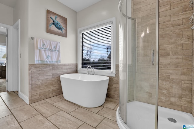 bathroom featuring tile walls, a healthy amount of sunlight, a stall shower, and tile patterned floors