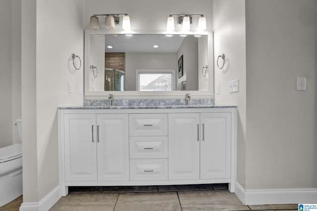 bathroom with double vanity, a stall shower, toilet, and a sink