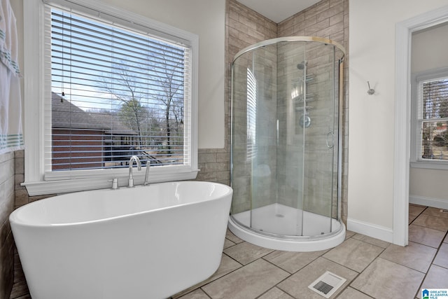 full bath with visible vents, a stall shower, a freestanding bath, tile patterned floors, and tile walls