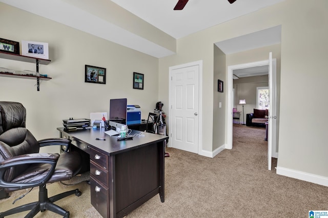 office space with light colored carpet, a ceiling fan, and baseboards