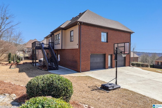 view of side of home with stairs, driveway, brick siding, and an attached garage