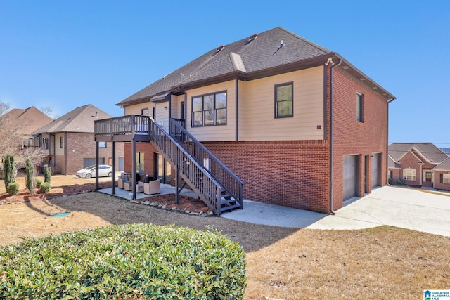 rear view of house with a patio, an attached garage, stairs, concrete driveway, and brick siding