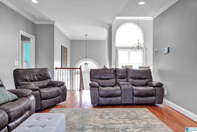 living room featuring baseboards, wood finished floors, a chandelier, and crown molding