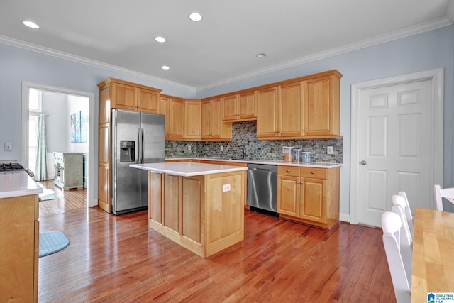 kitchen featuring ornamental molding, light wood-style flooring, a center island, stainless steel appliances, and light countertops