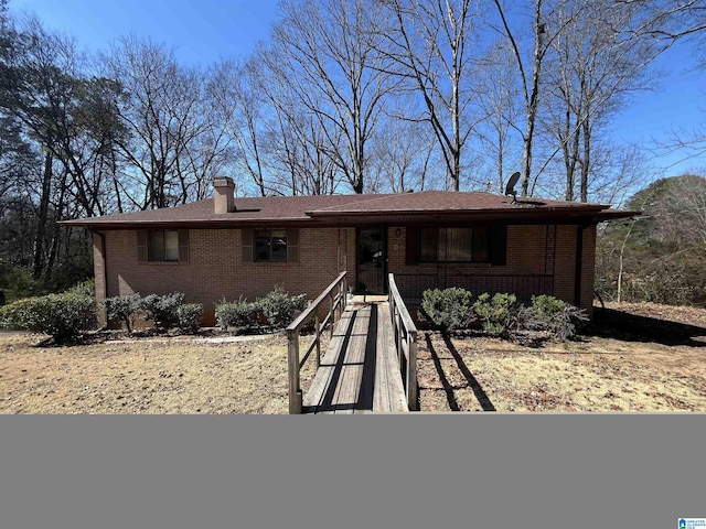 ranch-style house with brick siding, covered porch, and a chimney