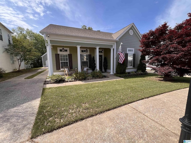 view of front facade featuring driveway, covered porch, and a front yard