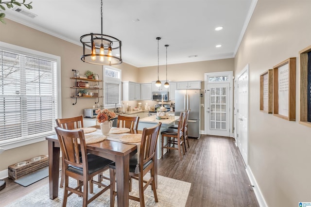 dining space featuring dark wood-style floors, visible vents, a wealth of natural light, and ornamental molding