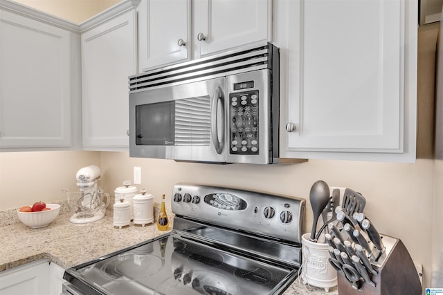 kitchen with stainless steel appliances, light stone countertops, and white cabinets