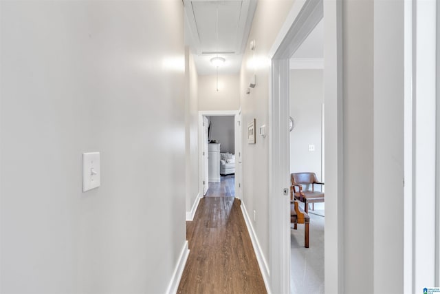 hall with dark wood finished floors, attic access, and baseboards