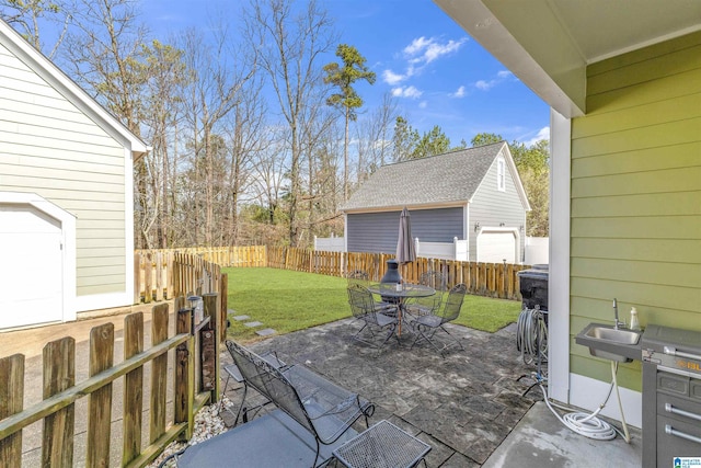 view of patio / terrace featuring a fenced backyard, outdoor dining space, an outdoor structure, and a sink