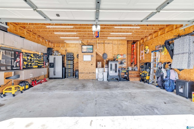 garage featuring a workshop area and stainless steel refrigerator with ice dispenser