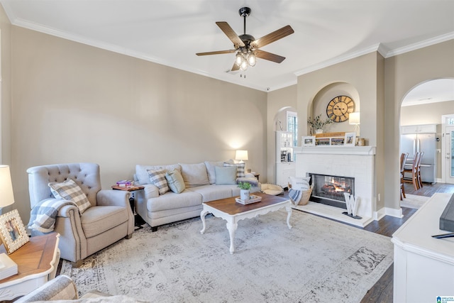 living room with a ceiling fan, crown molding, wood finished floors, and arched walkways