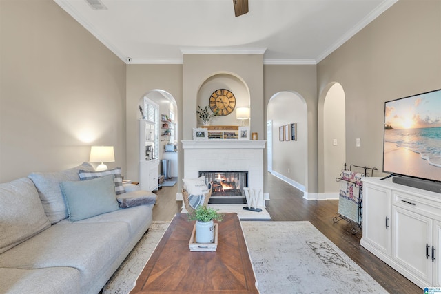 living room featuring dark wood finished floors, crown molding, baseboards, and arched walkways