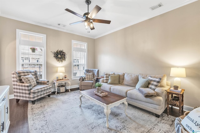 living room with crown molding, wood finished floors, visible vents, and ceiling fan