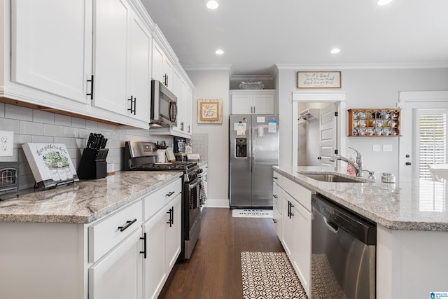 kitchen with white cabinets, ornamental molding, appliances with stainless steel finishes, and a sink