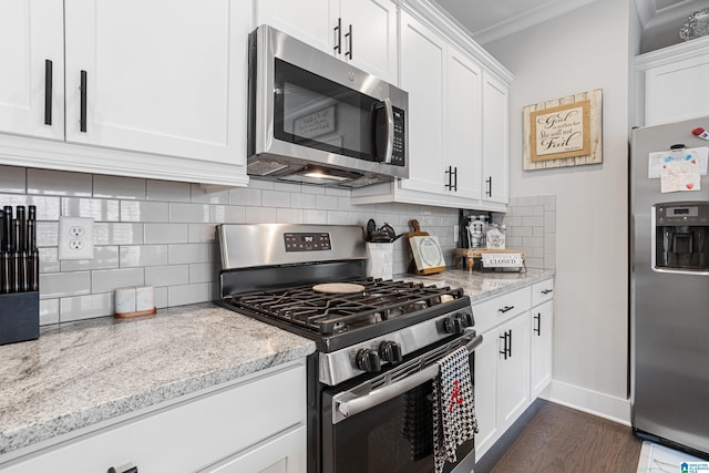 kitchen featuring backsplash, appliances with stainless steel finishes, white cabinets, and crown molding