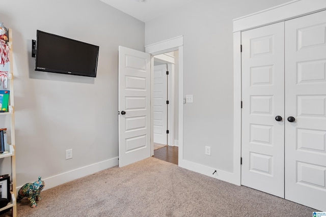 carpeted bedroom with a closet and baseboards