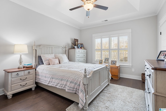 bedroom with baseboards, visible vents, a tray ceiling, ceiling fan, and dark wood-type flooring