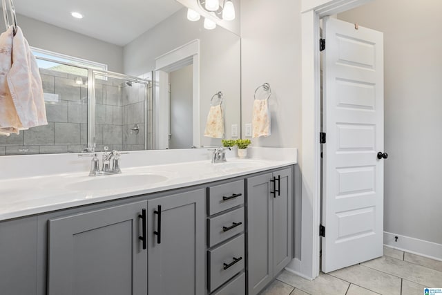 full bath with double vanity, a stall shower, tile patterned floors, and a sink