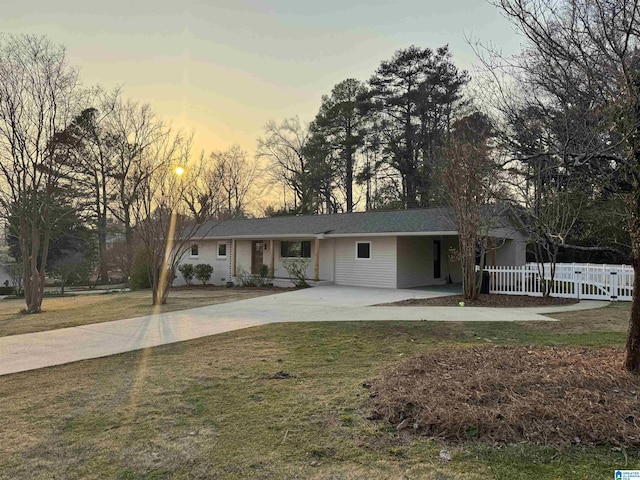 ranch-style house with a yard, concrete driveway, and fence