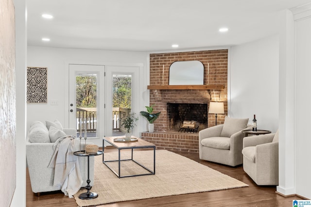 living room featuring recessed lighting, a brick fireplace, and wood finished floors