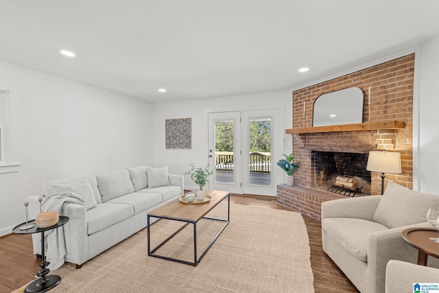 living area with recessed lighting, a brick fireplace, and wood finished floors