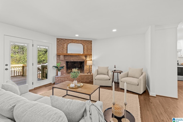 living area featuring a brick fireplace, recessed lighting, wood finished floors, and baseboards