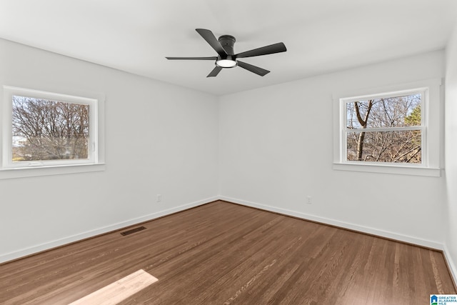 empty room with ceiling fan, visible vents, baseboards, and wood finished floors