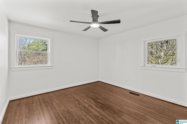 unfurnished room with dark wood finished floors, baseboards, visible vents, and ceiling fan