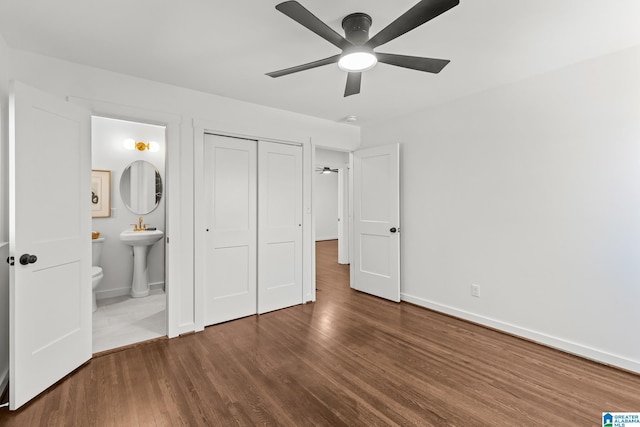 unfurnished bedroom featuring a sink, wood finished floors, a closet, and baseboards