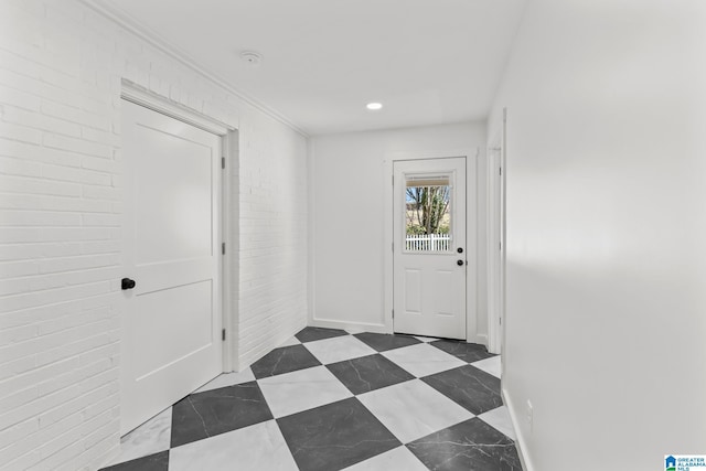 interior space featuring tile patterned floors, brick wall, and baseboards