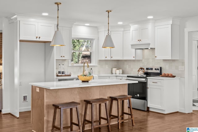 kitchen with white cabinets, stainless steel range with electric stovetop, a kitchen island, and light countertops