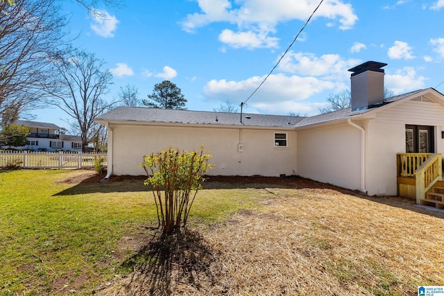 rear view of property with a yard, fence, brick siding, and a chimney