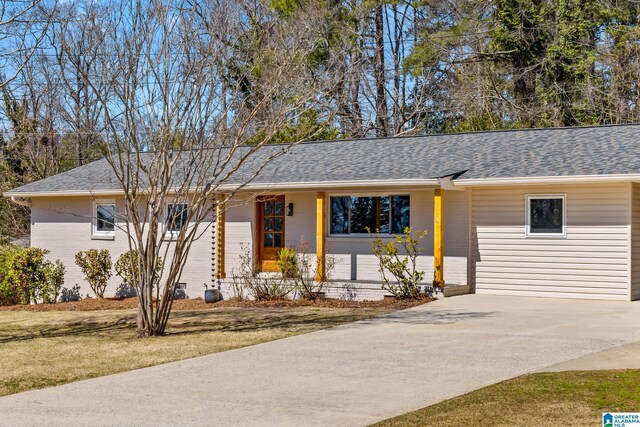 ranch-style house featuring a front yard, driveway, and a shingled roof