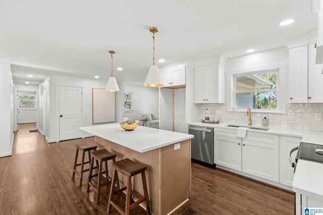 kitchen featuring a sink, backsplash, dark wood-style floors, a center island, and appliances with stainless steel finishes