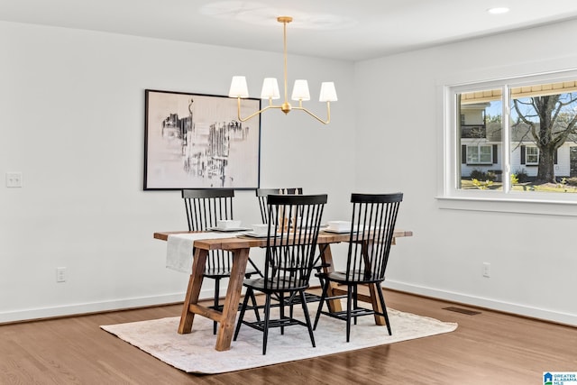 dining area featuring an inviting chandelier, wood finished floors, visible vents, and baseboards