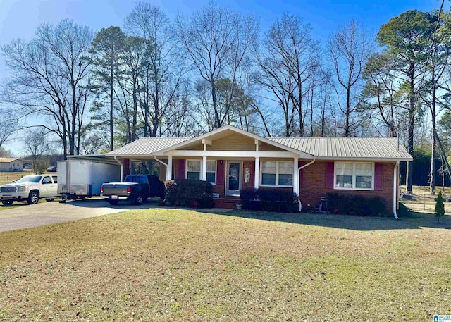 ranch-style house featuring brick siding, an attached carport, a front yard, metal roof, and driveway