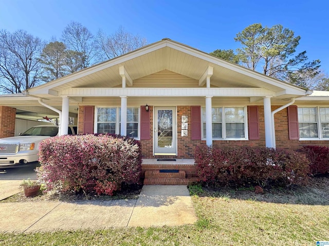 bungalow-style home with an attached carport, brick siding, and covered porch
