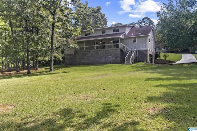 back of property with stairway, a lawn, and stone siding