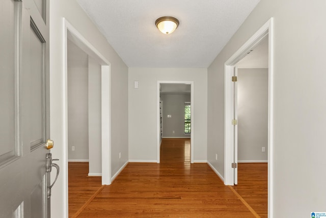 entryway featuring a textured ceiling, light wood-type flooring, and baseboards