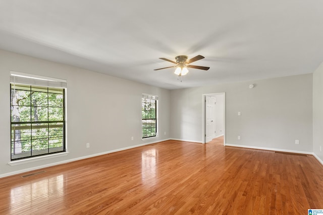 empty room featuring visible vents, ceiling fan, light wood-type flooring, and baseboards