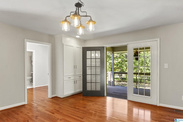 entryway featuring a notable chandelier, visible vents, baseboards, and wood finished floors