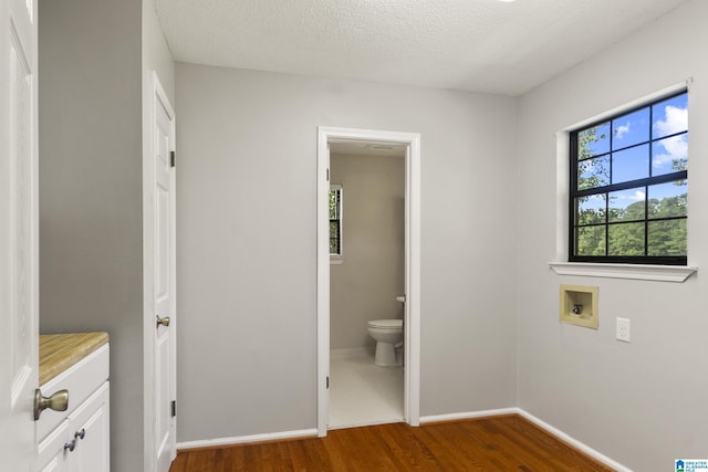 bathroom with a textured ceiling, toilet, baseboards, and wood finished floors