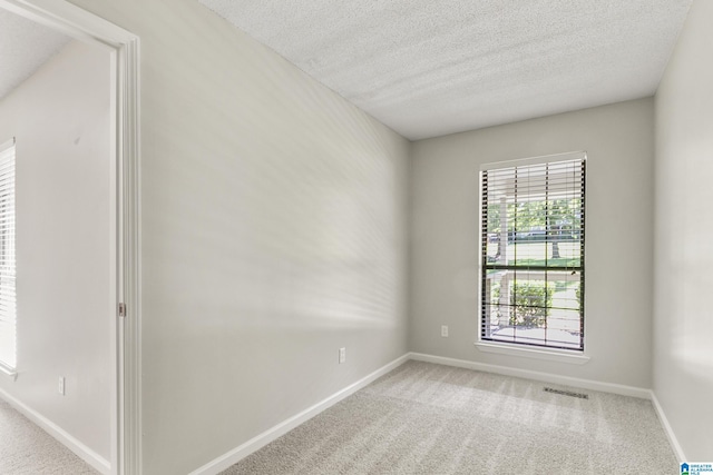 empty room featuring baseboards, visible vents, carpet floors, and a textured ceiling