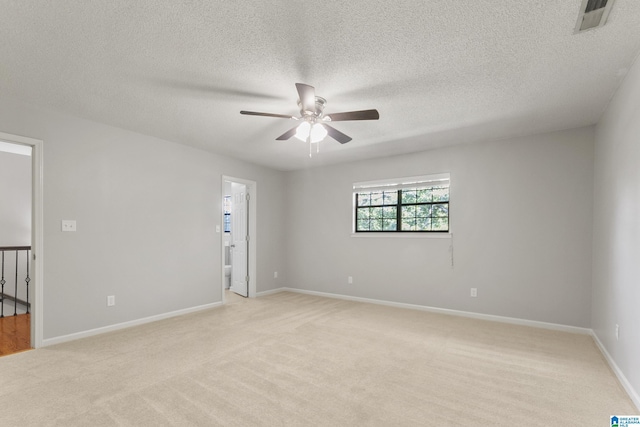 spare room with visible vents, light colored carpet, baseboards, and a ceiling fan