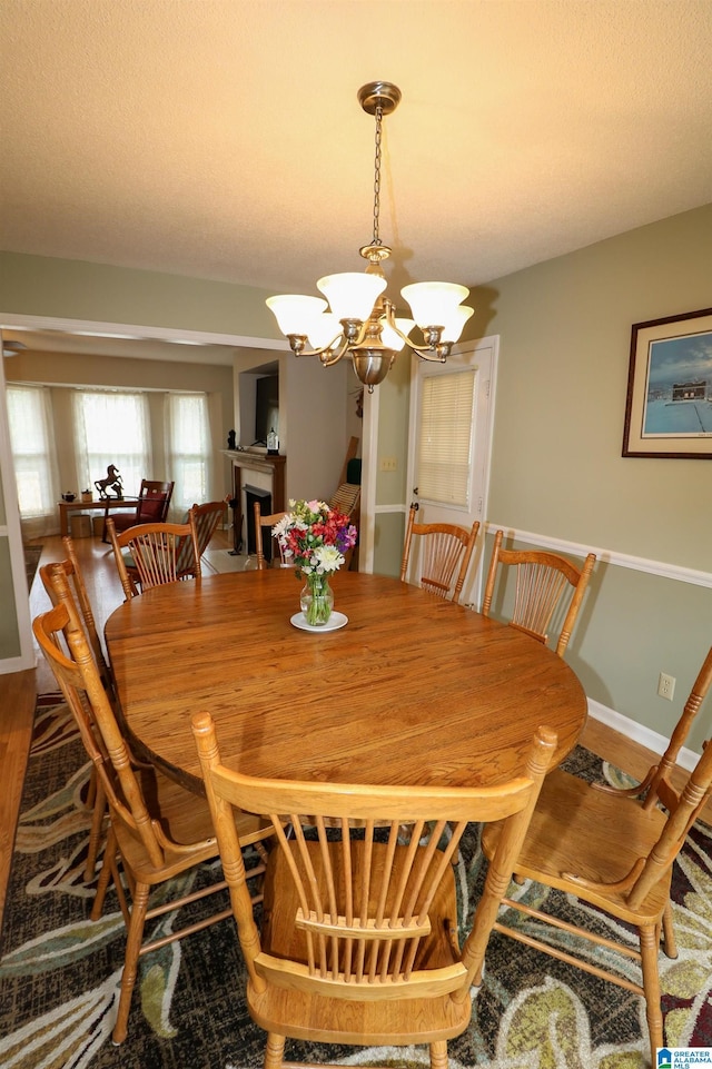 dining area with an inviting chandelier, wood finished floors, a fireplace, and baseboards